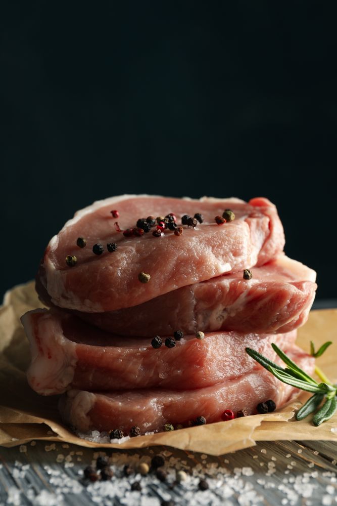 Composition with raw meat for steak and spices on wooden background