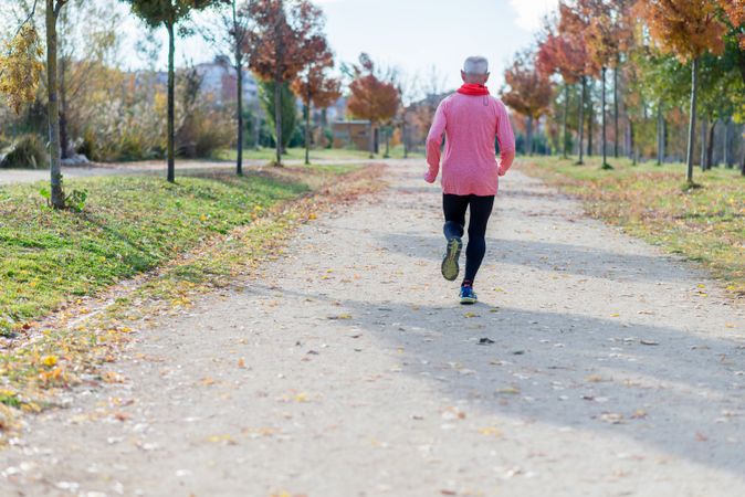 Back of older man jogging in park during autumn