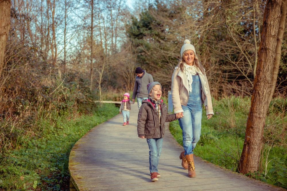 Happy family of four walking on trail in forest