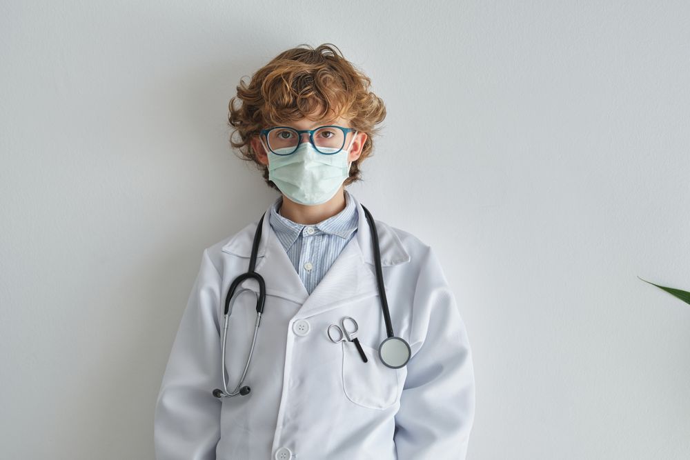 Boy doctor in sterile mask and uniform with stethoscope