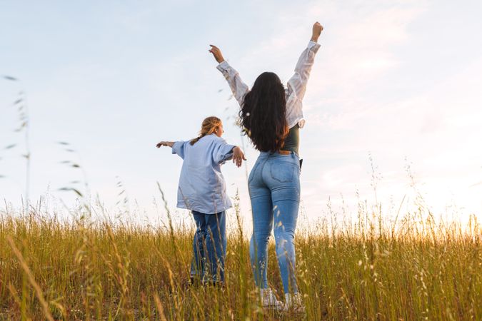 two women friends enjoying in a field at sunset