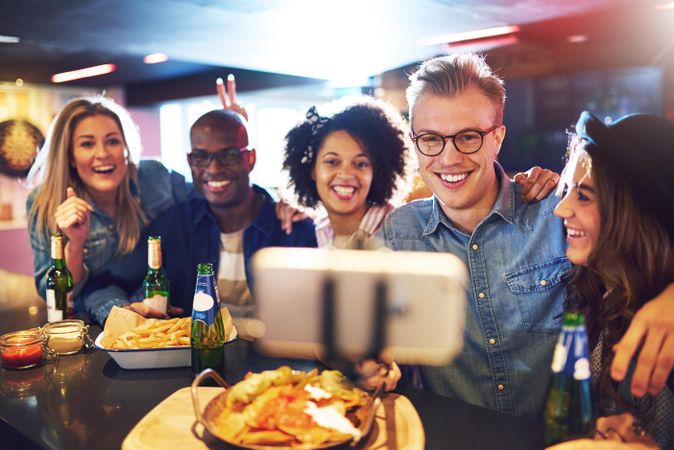 Multi-ethnic group of smiling people posing for a photo at a bar