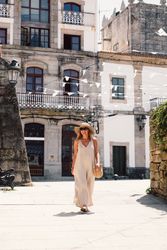Woman in hat walking along sunny street