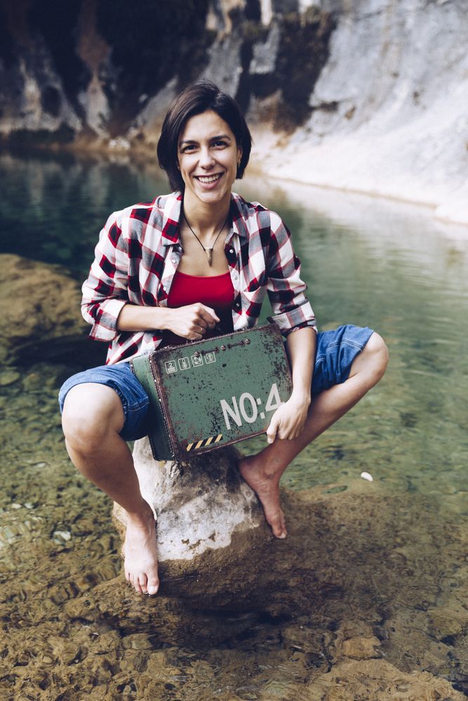 Woman with picnic case on rock in water