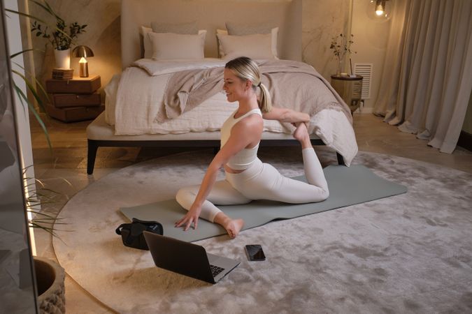 Sportswoman sitting on mat and doing yoga in Pigeon pose