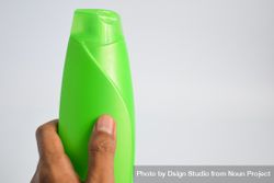 Hand holding blank green shampoo bottle 0v33LR