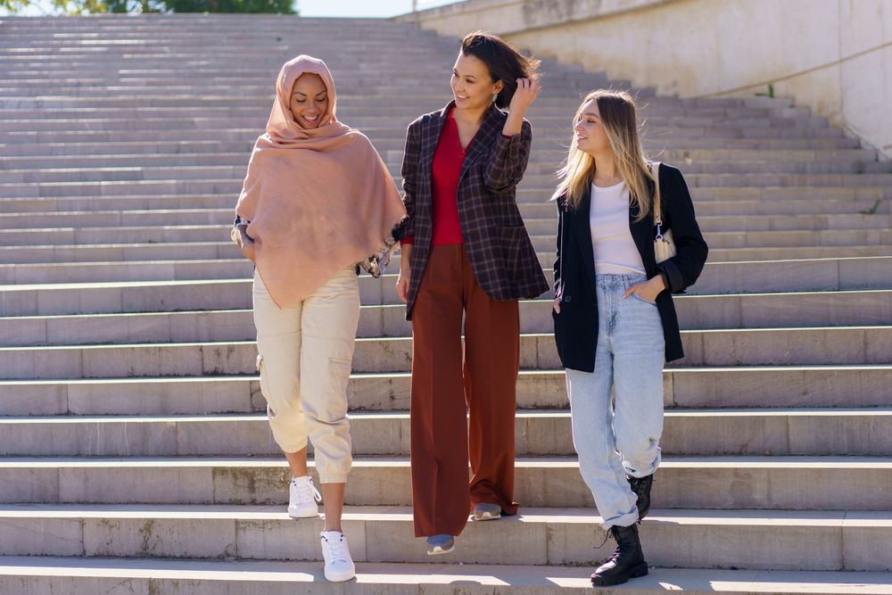 Female friends descending outside staircase and talking on sunny day