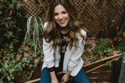 Smiling woman sitting on planter in garden