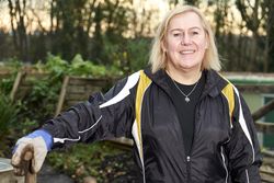Older woman smiling outside wearing gardening gloves