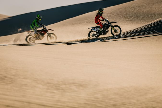Motocross biker riding over dunes in desert