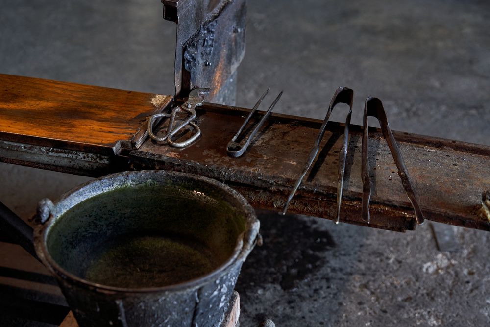 Old metal tools on wooden table in glass factory
