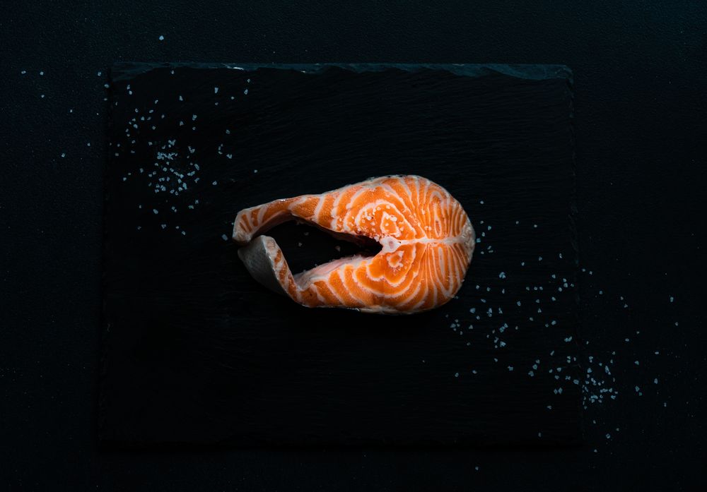 Top view of salmon steak on dark counter with copy space