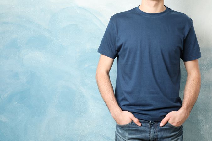 Men in blank blue t-shirt against color background, space for text