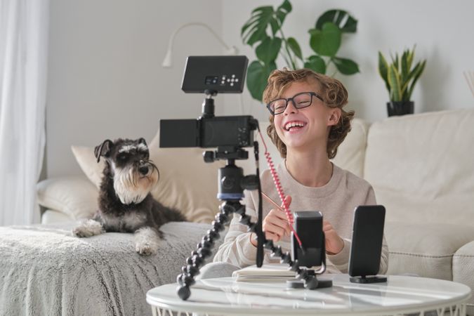 Laughing boy looking at professional camera while shooting video