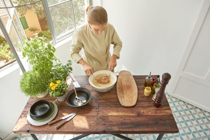 Young woman cooking steak tartare in kitchen