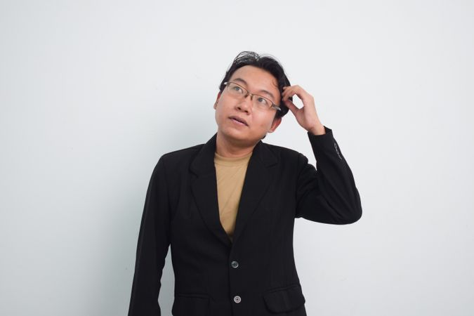 Thoughtful Asian businessman scratching head