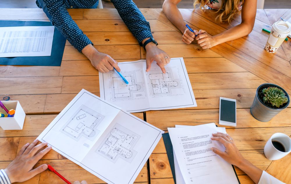 Top view of unrecognizable architects in a work meeting looking at construction plans