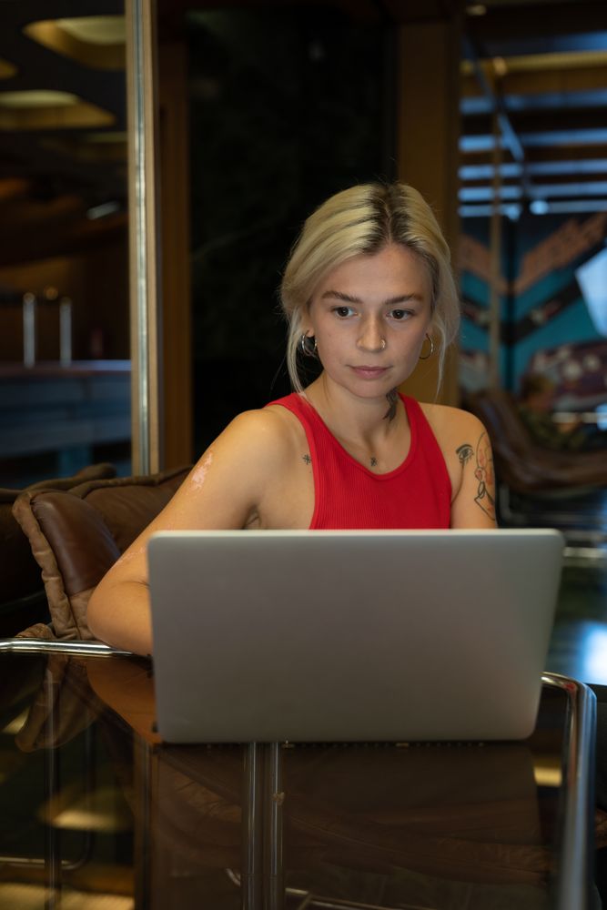 Young woman in red tank top working on laptop in a coffee shop