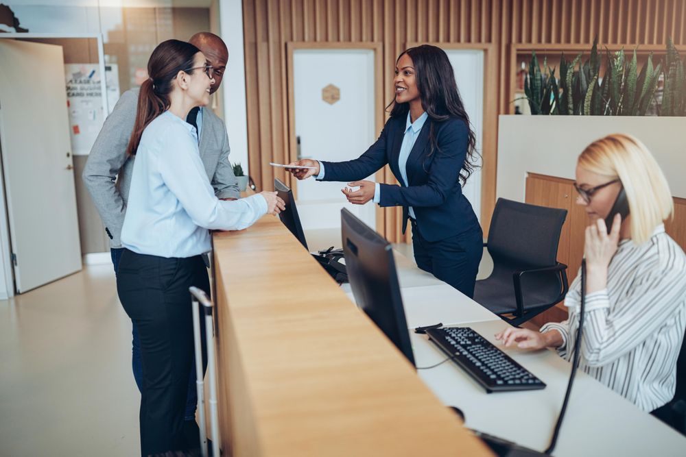 Two guests are greeted after arriving at the front desk