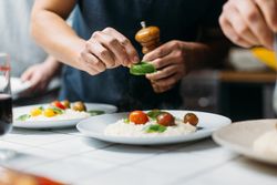 Close up of man placing basil on risotto