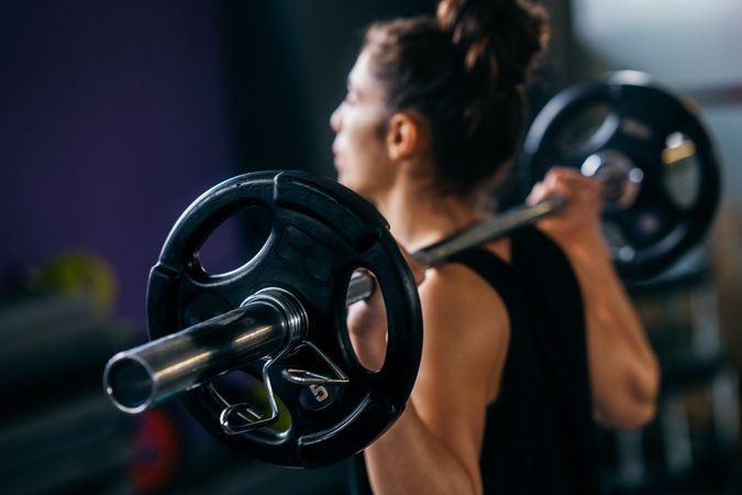 Fit woman with barbell over her shoulders