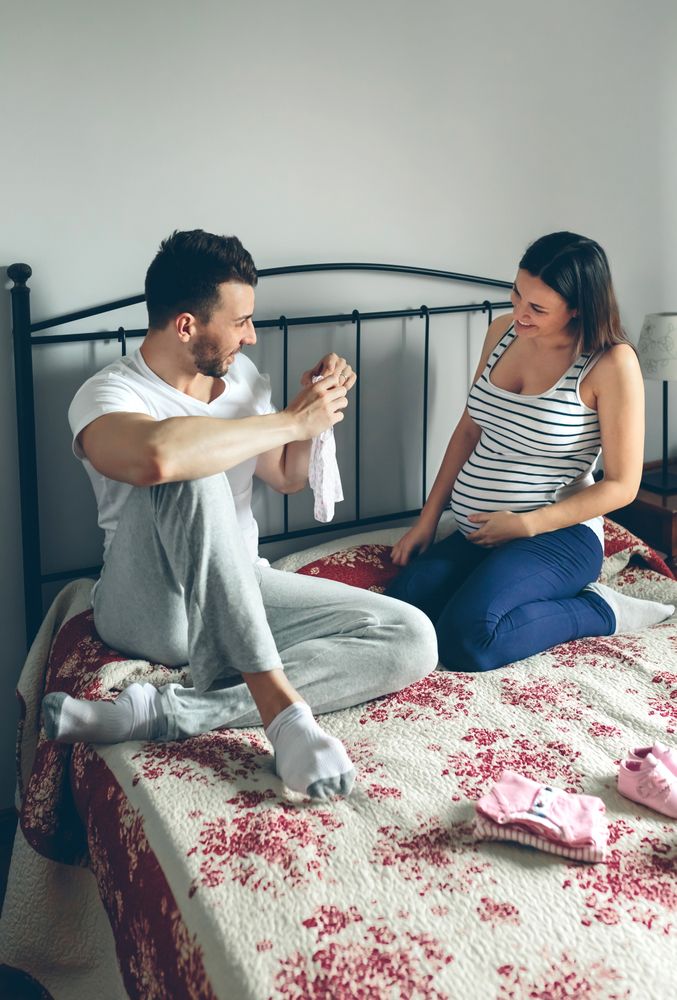 Man showing baby clothes to pregnant woman