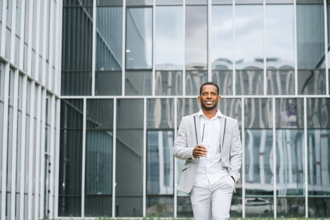 Black man with coffee standing in downtown