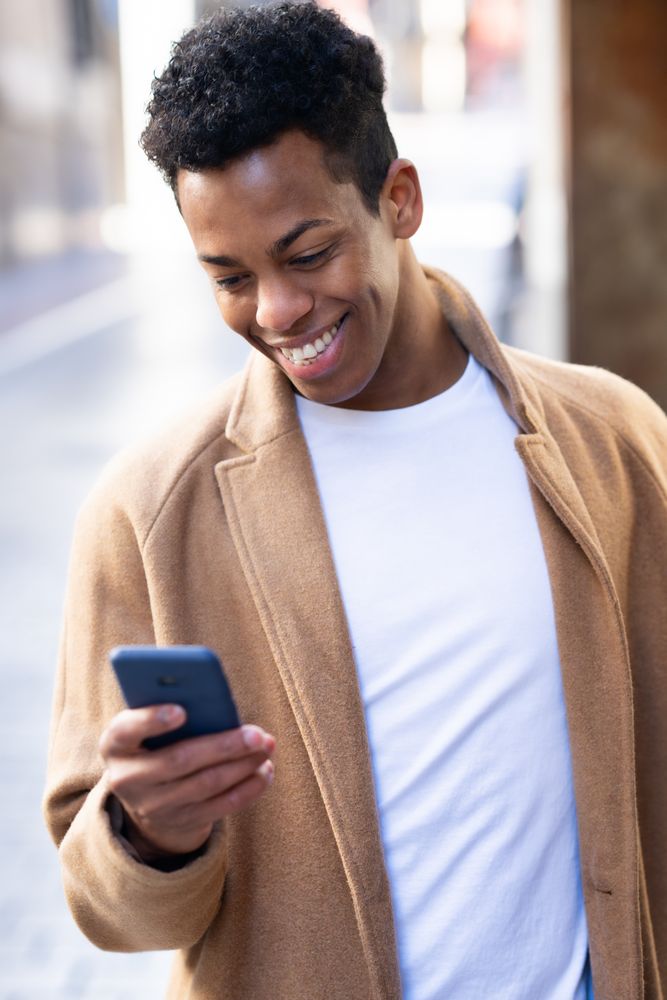 Cuban male smiling while looking down at his phone