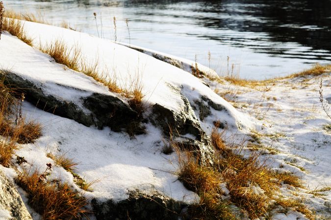 Rocky peaceful shore with snow crust in sunrays