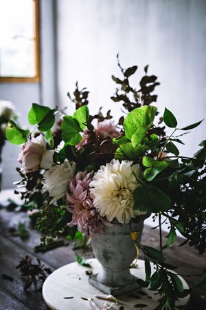 Composition of flowers and plants in vintage vase on board
