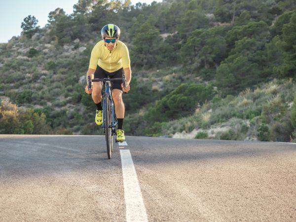 healthy man riding a bicycle on a mountain road in a sunny day
