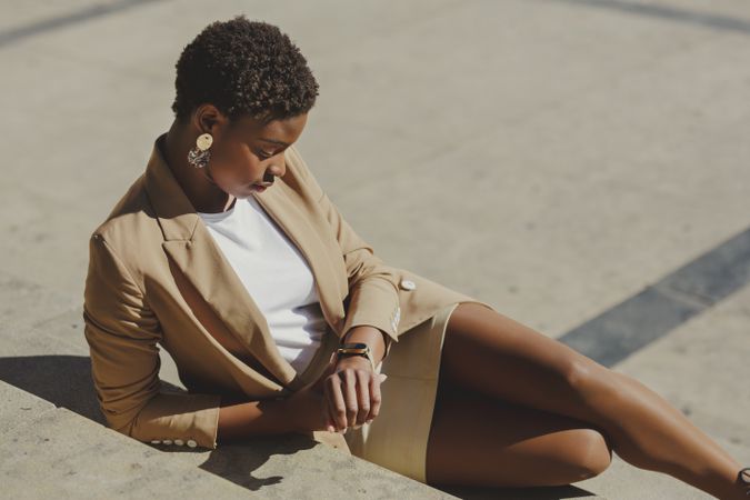 Stylish Black woman sitting on steps on street