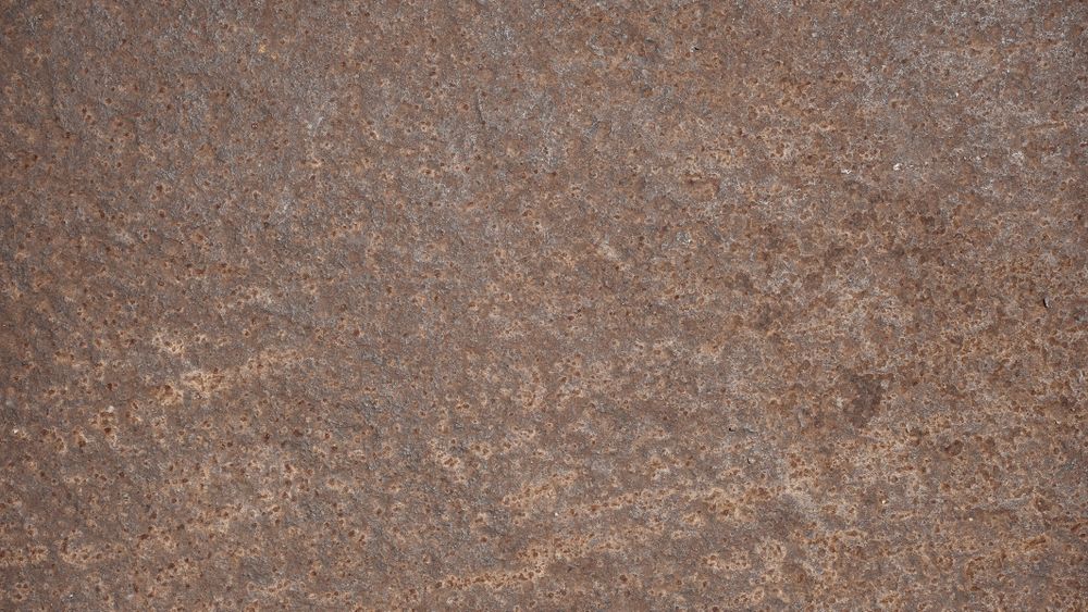 Corroded metal surface with small holes and aged rust texture