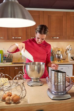 Female pastry chef filing bowl with cream