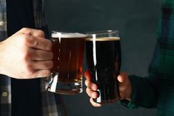 Two men in checkered shirts cheers with beer