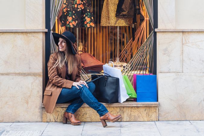 Content young woman in casual outfit resting on street after shopping
