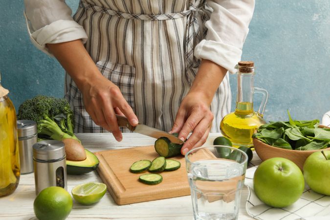 Woman cutting cucumber on wooden table