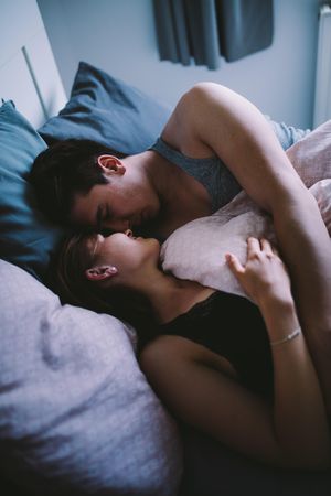 Young man and woman embrace in bed