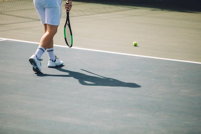 Man in white sportswear playing tennis on hard court
