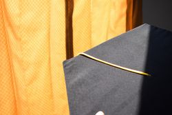 Top view of graduation cap with yellow tassel on yellow material background