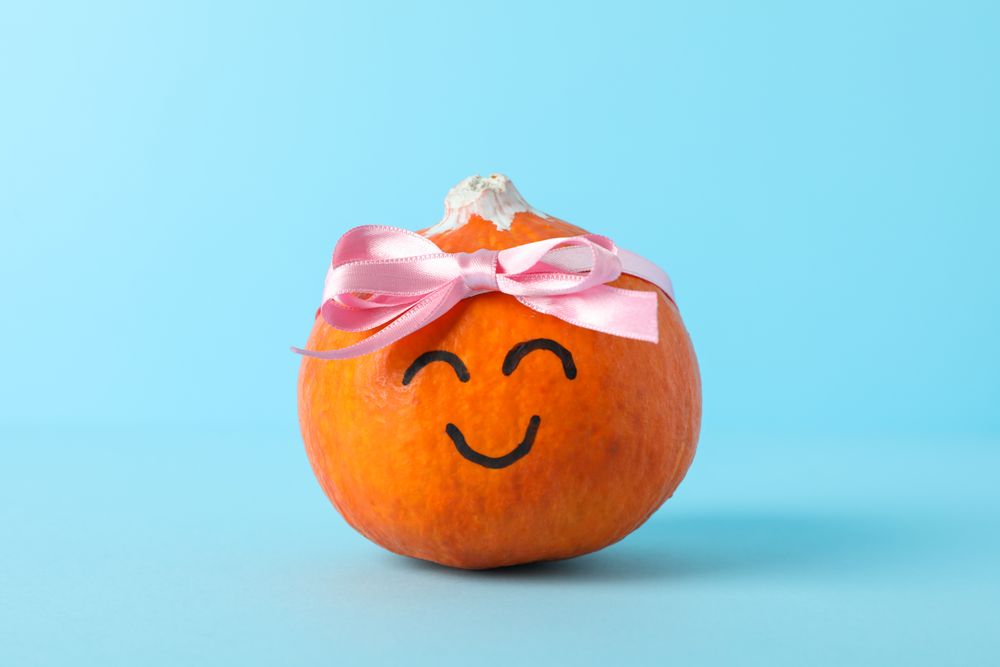 Happy pumpkin with bow on blue background, space for text