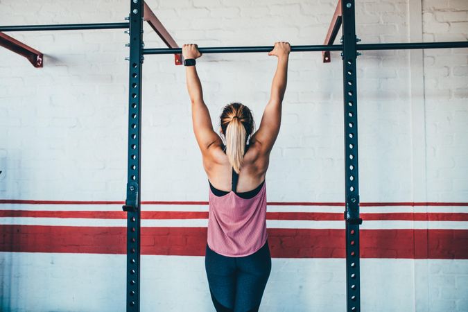 Woman hanging from a bar in the gym
