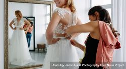 Female trying on wedding dress in a shop with women assistant 4NeZD5