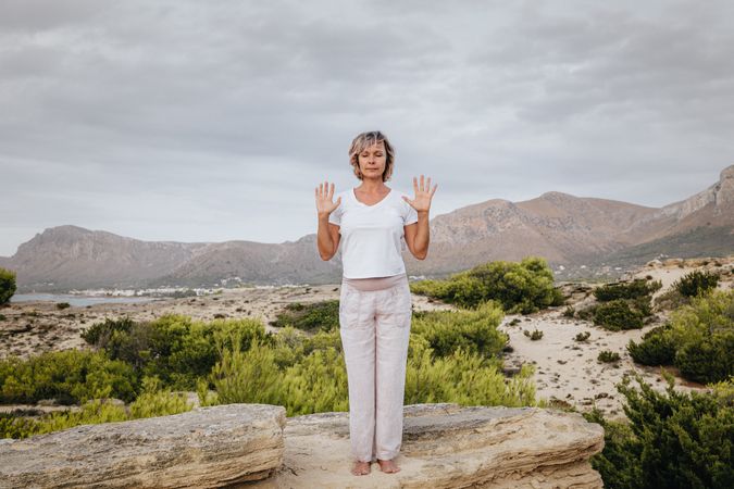 Barefoot woman meditating on stone