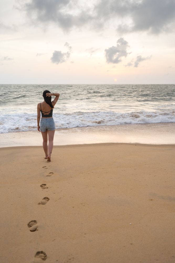 Woman in beachwear walking on sand barefoot