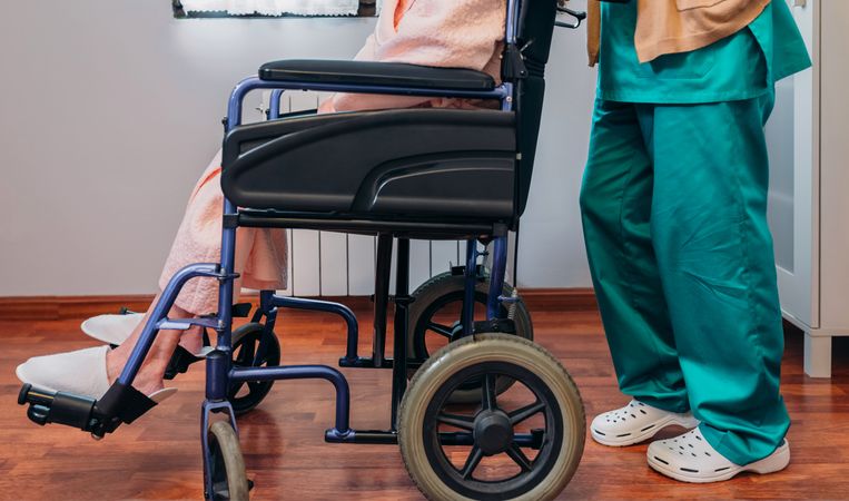 Doctor carrying older patient in a wheelchair