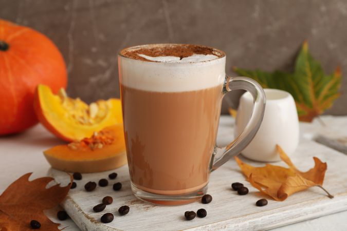 Composition with glass cup of pumpkin latte on light background
