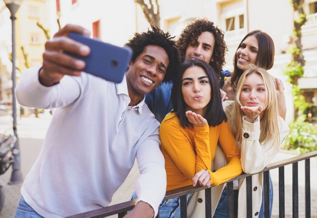 Multi-ethnic group of friends taking selfies together outside