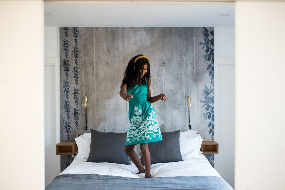 Black girl with headphones dancing on bed