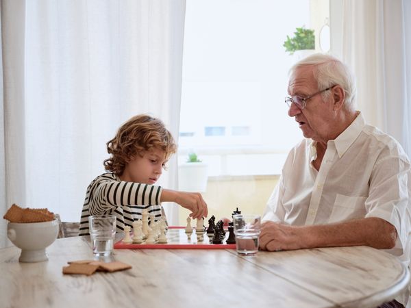 Grandfather teaching grandson to play chess